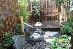 a small garden with rocks, plants and a wooden bench in the middle of it