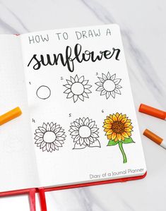 an open notebook with sunflowers drawn on it and some crayons next to it