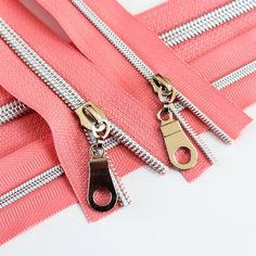 there are several zippers with metal handles on the white table and one is pink