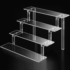 three tiered clear glass shelf against a black background