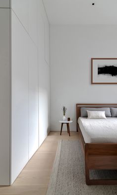 a bedroom with white walls and wood furniture, along with a large bed in the middle