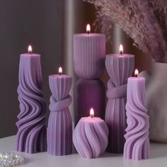 purple candles are sitting on a table next to pearls and a vase with flowers in it