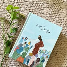 a book sitting on top of a white blanket next to a green leafy plant