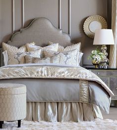 a bed with silver and gold comforter in a bedroom next to a white stool