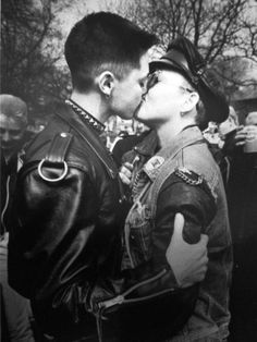 a man and woman kissing each other in front of a group of people on the street