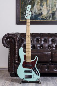 a blue guitar sitting on top of a wooden floor next to a brown leather couch