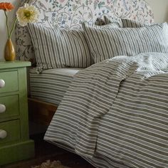 a bed with striped comforter and pillows on it next to a green night stand