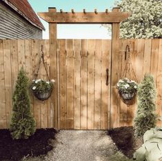 two hanging planters on the side of a wooden fence