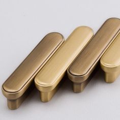 three brass cabinet knobs on a white surface