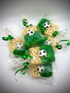 four bags filled with rice krispy treats covered in soccer balls and green ribbones