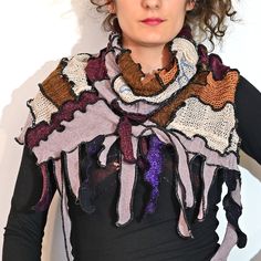 a woman with curly hair wearing a multicolored knitted scarf and black top