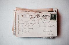 an old postcard with writing on it and two envelopes stacked next to each other