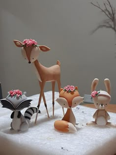 a cake decorated with animals and flowers on top of a white tablecloth covered in frosting