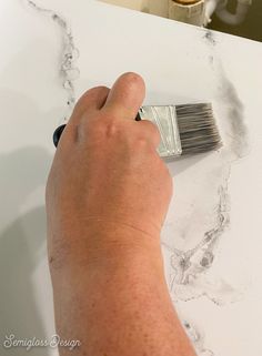 a person using a brush to paint marble