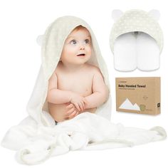 a baby wrapped in a white blanket next to a box and slippers on the floor