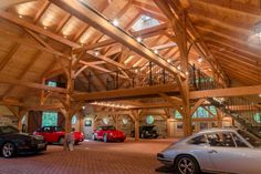 two cars are parked in a large garage with high ceilings and wooden beams on the ceiling