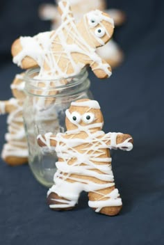 two gingerbreads with white icing on them are in front of a jar