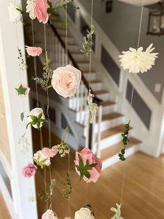 some pink and white flowers are hanging from the ceiling in front of a stair case