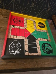 a wooden board with different colored squares and designs on the front, sitting on top of a table