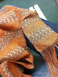 an orange scarf with silver sequins on it sitting on someone's lap