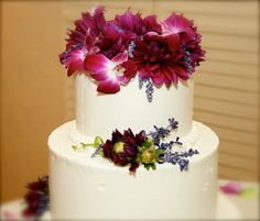 a three tiered white cake with purple flowers on top