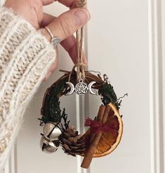 a person holding a christmas ornament hanging from a door handle with pine cones and cinnamons on it