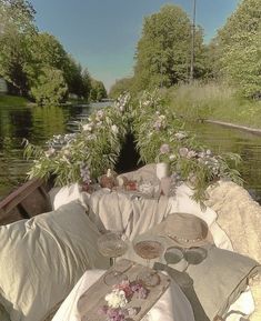 there is a couch with pillows on it next to the water and flowers in vases