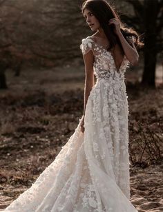 a woman in a wedding dress is walking through the woods with her back to the camera