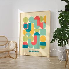 a framed poster with the word bauhaus on it in front of a chair and potted plant