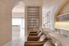 a long row of brown leather chairs sitting in front of two sinks and a mirror