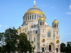 a large white building with gold domes on it's sides and trees in the foreground