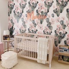 a baby's room with cactus wallpaper and crib in the foreground