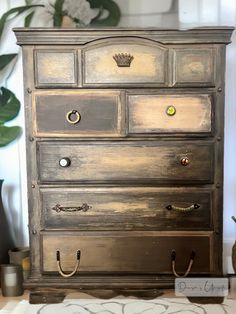 an old dresser is painted gray with gold paint and knobs on the drawers,