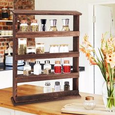 a wooden spice rack filled with spices on top of a counter next to a vase full of flowers