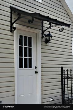 a white front door with a black iron frame and light fixture on it's side