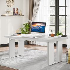 a white desk with a computer on it in front of a window and a clock