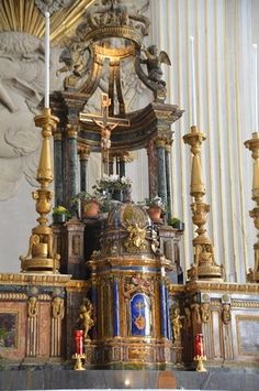 an ornate gold and blue alter in a church with candles on each side, surrounded by statues