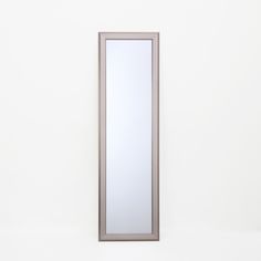 a tall mirror sitting on top of a white wall