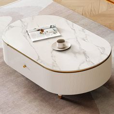 a white marble coffee table with gold trim around the edge and a magazine on top