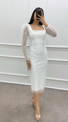 a woman taking a selfie wearing a white dress with sheer sleeves and beading