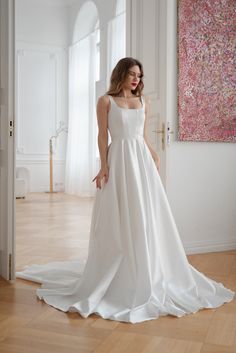 a woman in a white dress standing on a wooden floor