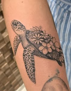 a tattoo with a turtle and flowers on it