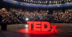 a large group of people sitting in front of a stage with the words ted on it