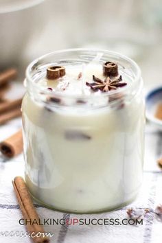 a glass jar filled with some kind of liquid next to cinnamon sticks and other spices