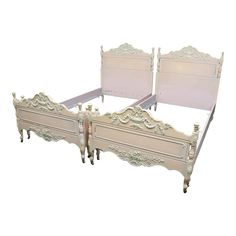 two white beds with ornate headboards and foot boards