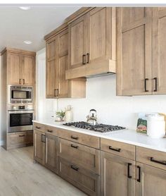 a kitchen with wooden cabinets and white counter tops is pictured in this image, there is a tea kettle on the stove