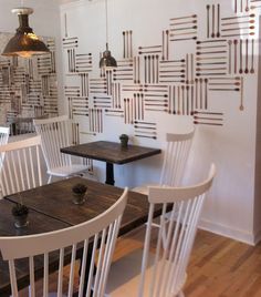 two white chairs sitting at a wooden table in front of a wall with lines drawn on it