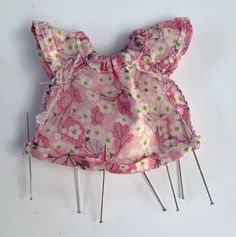 a pink dress with flowers on it and pins attached to the back of each piece