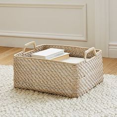 a wicker basket with books in it on a rug