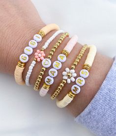 a woman's arm with bracelets on it, including letters and beads in different colors